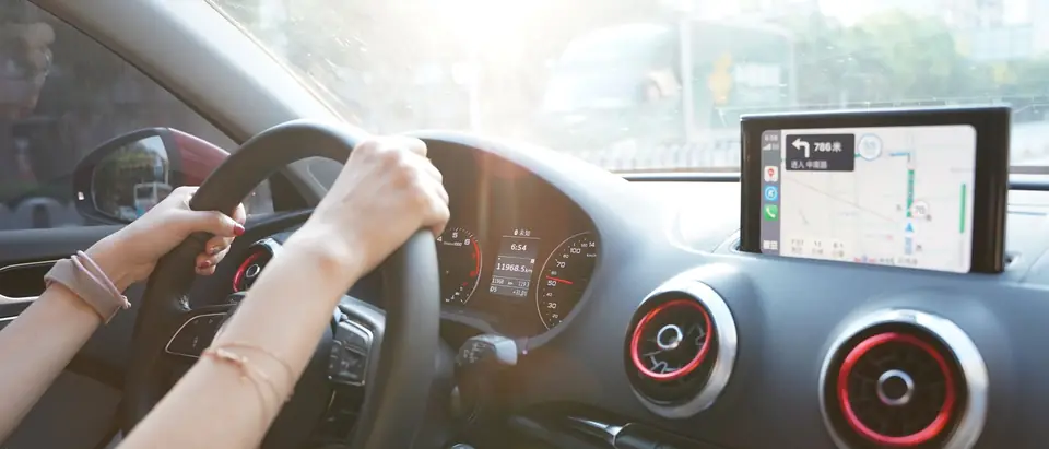 Hands on the wheel with a map on the dash screen
